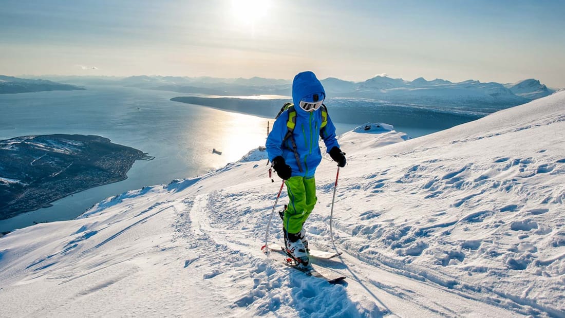 En person på ski står på toppen av et fjell.