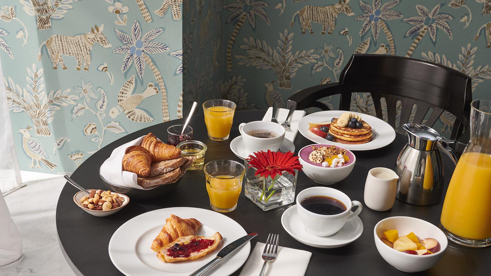 Flott frokost med pannekaker, croissants, frukt, rykende varm kaffe og yoghurt.