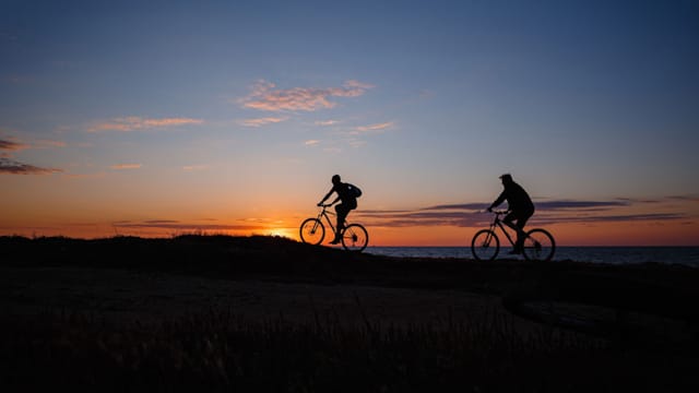 Syklister i solnedgang.