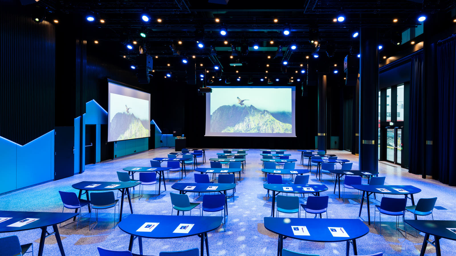 Lofotsalen hos Thon Hotel Svolvær i blått lys og store skjermer.