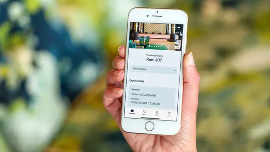 En dame holder mobiltelefon i hånden og har sjekket ut via appen