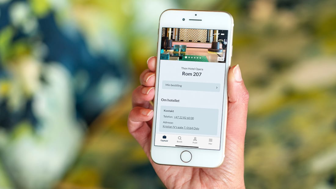 Jente med åpnet Thon Hotels app på sin iPhone 