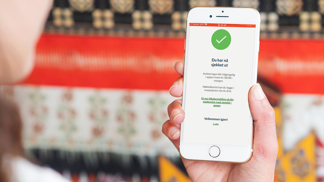 En dame holder mobiltelefon i hånden og har sjekket ut via appen