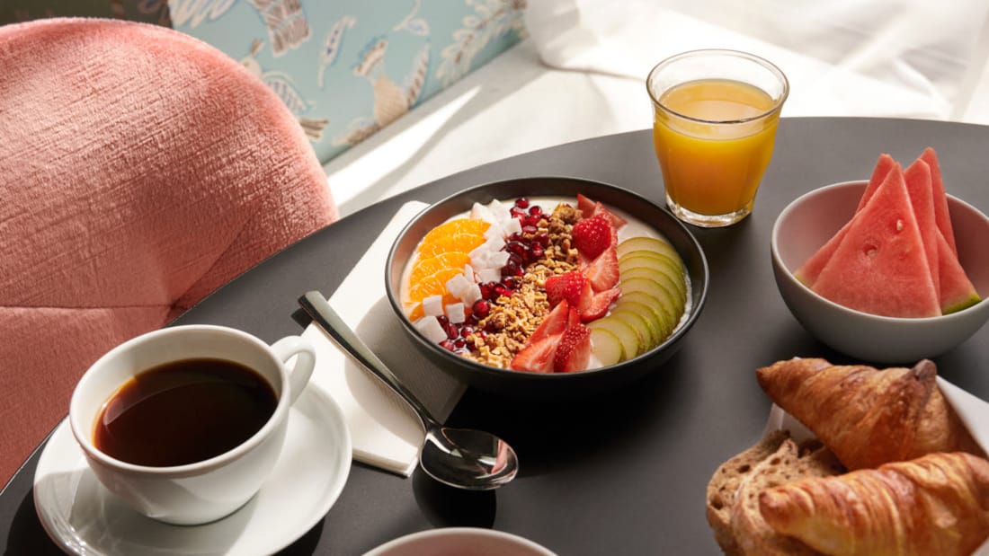 Detaljbilde av smoothiebowl, frukt, kaffe og bakverk på bordet