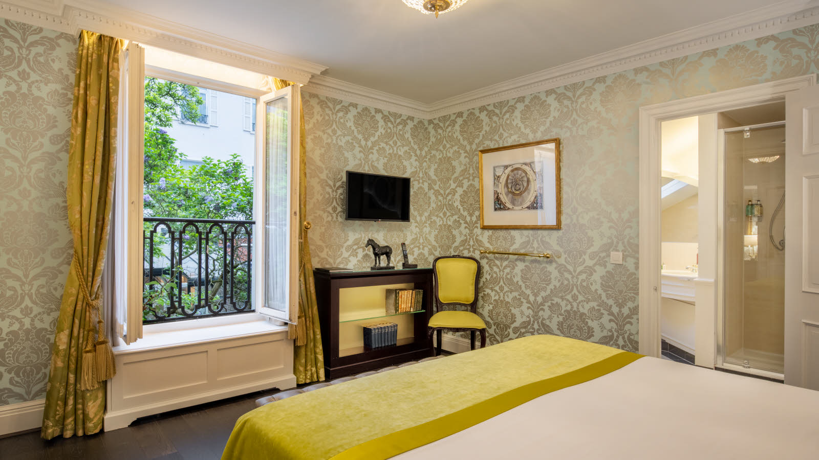 Et hotellrom med en koselig seng, en moderne TV og et stort vindu med vakker utsikt.