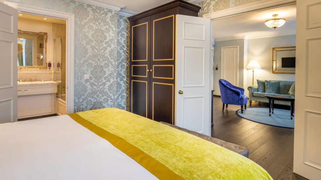 Suite på Stanhope hotell med dobbeltseng, garderobe stol og inngang mot bad og stue