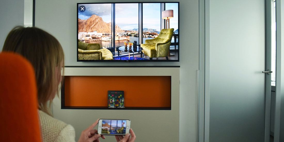 En som styrer TV'en med sin smarttelefon