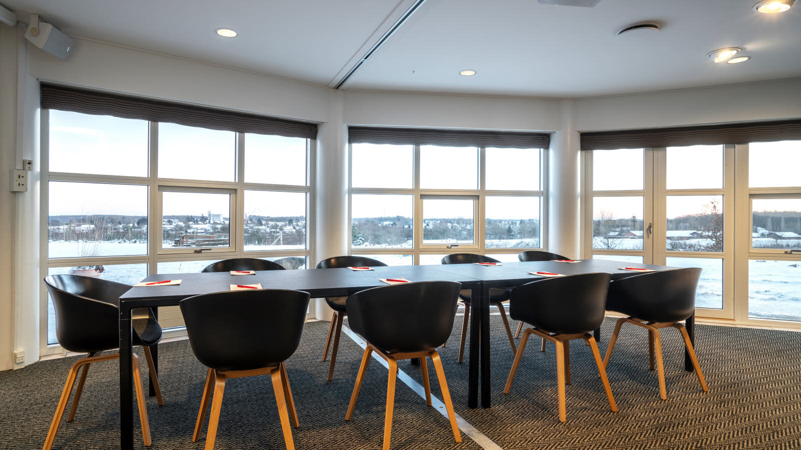 Nærbilde av bord og stoler i klasseromsoppsett. På bordene ligger penn og papir