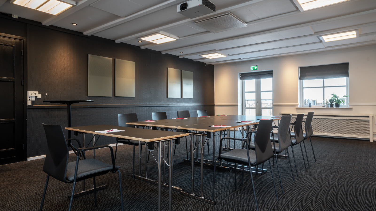 Nærbilde av bord og stoler i klasseromsoppsett. På bordene ligger penn og papir