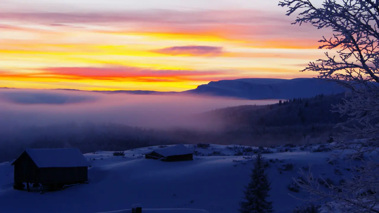 Snødekt landskap med hus i forgrunnen.