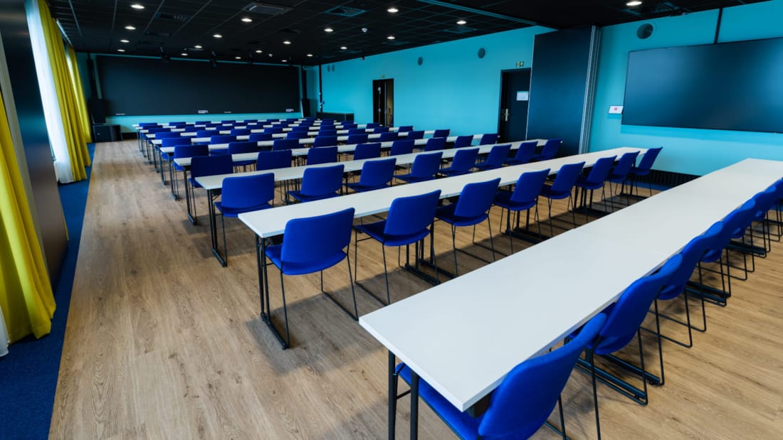 Konferanselokale i klasseromsoppsett med blå stoler, tv-skjerm og tavle