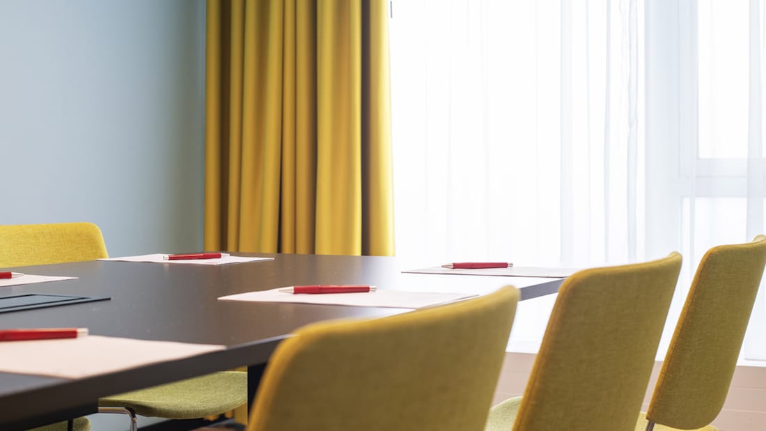 Thon Hotel Alta møterom stort bord med gule stoler ved lys vindu