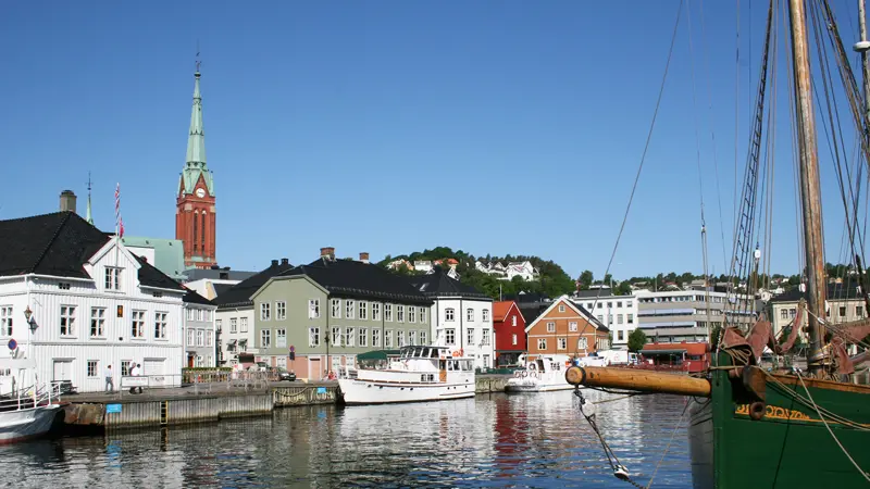 Havnen i Arendal med hus og båter langs bryggekanten