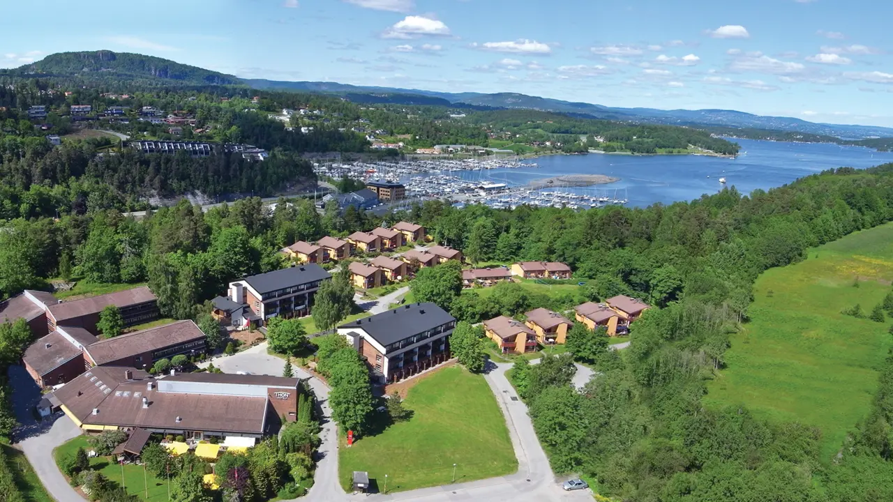 Et fugleperspektiv av Thon Hotel Vettre med en marina og fjell.