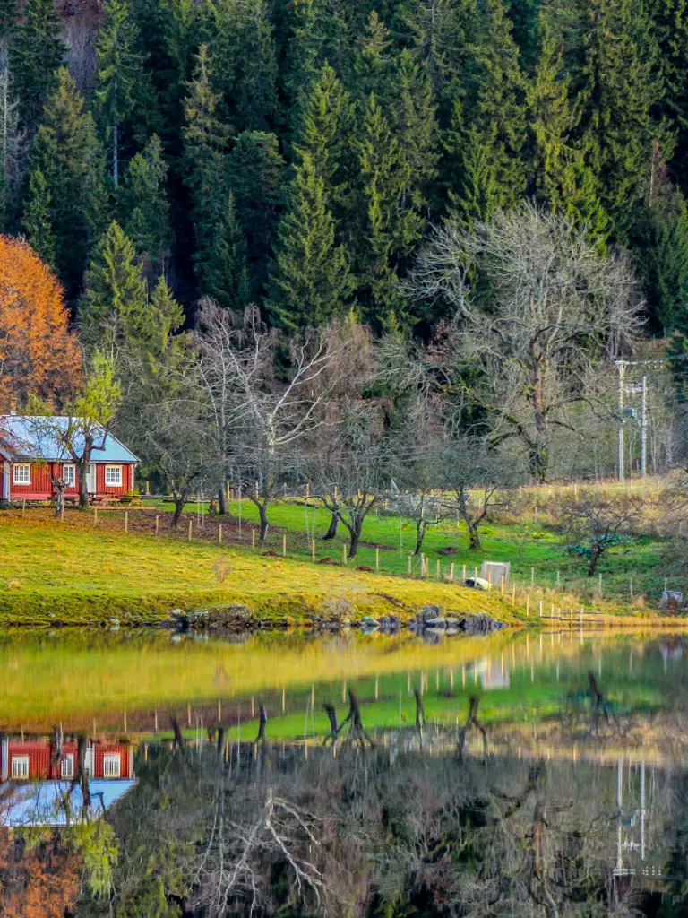 Et lite rødt hus ved kanten av en innsjø