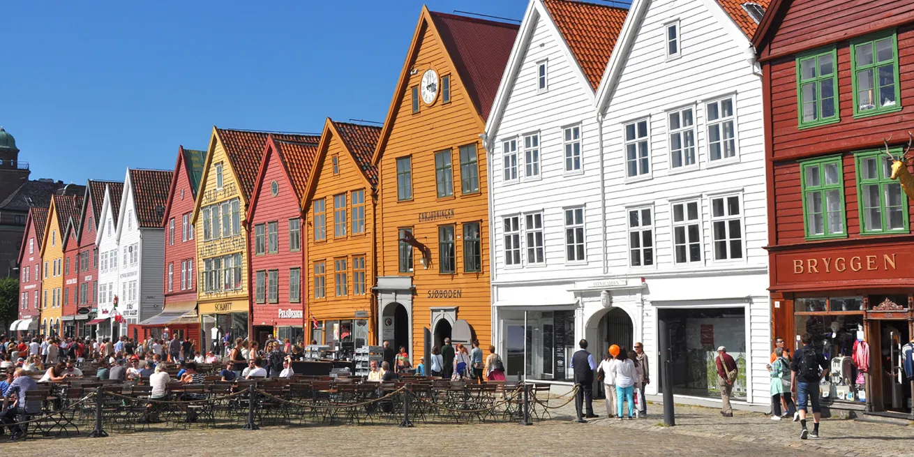 Bryggen i Bergen med et yrende folkeliv utenfor p&aring; sommerstid, p&aring; cafeer og i butikker
