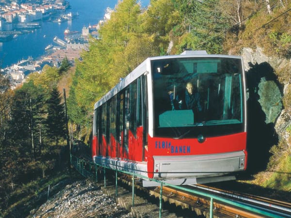 Bilde av Fløibanen, rødt og hvitt tog som kjører nedover et fjell.