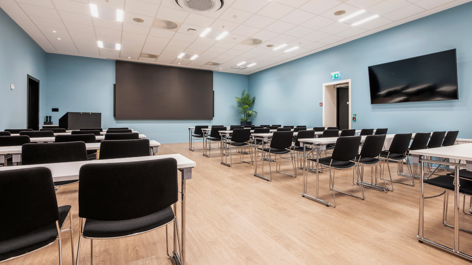 Konferanserom i klasseromsoppsett, skjerm i fornt og på siden.