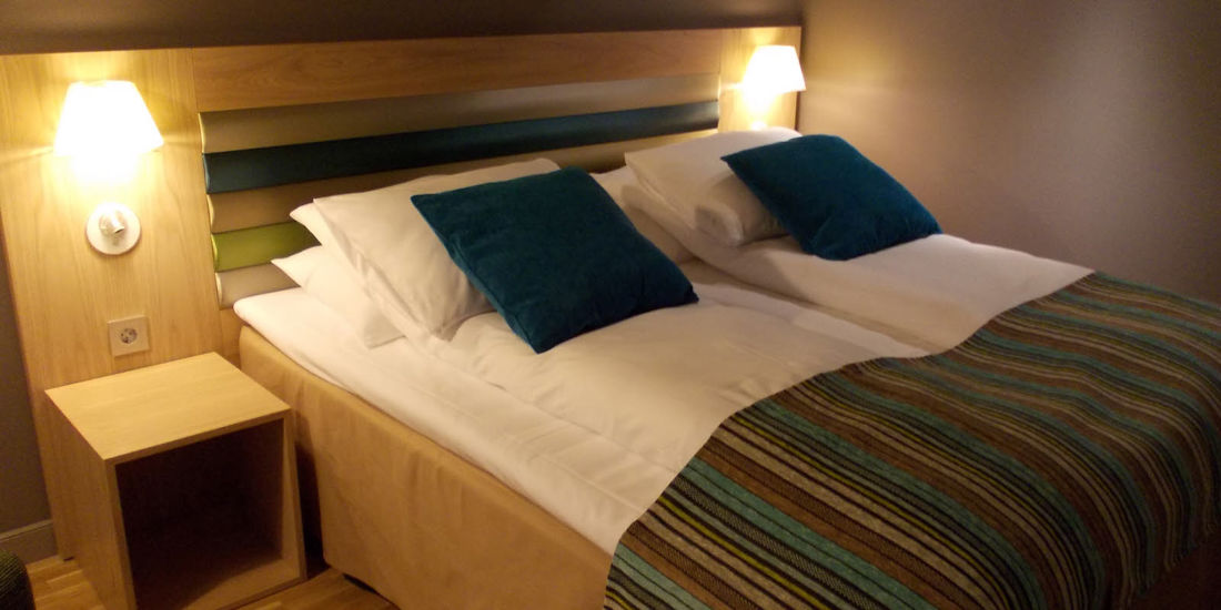 Nattbord og dobbeltseng med pynteputer og sengeteppe på Thon Hotel Brønnøysund
