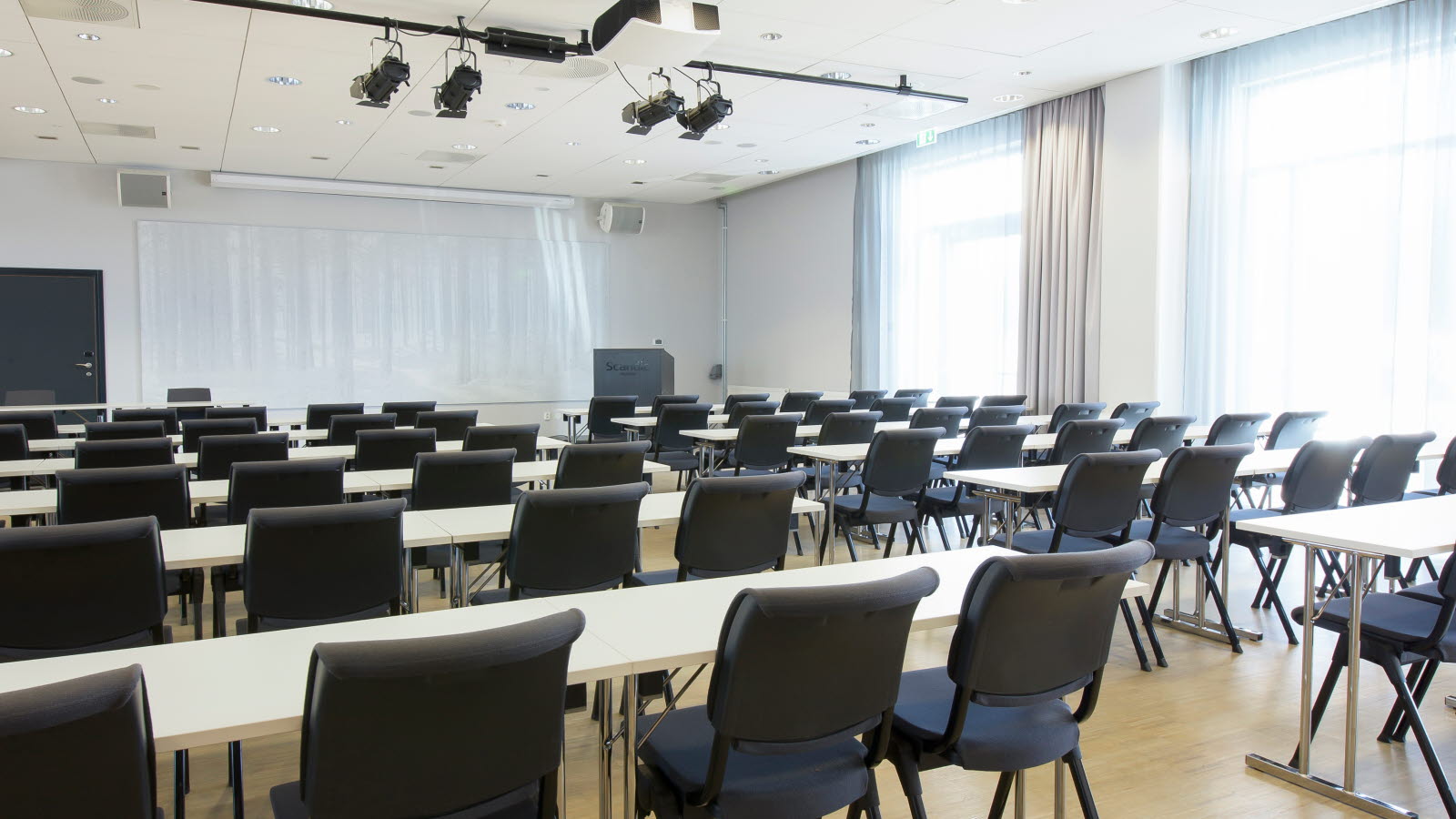 Møterom i klasseromoppsett med projektor, whiteboard og spotlights