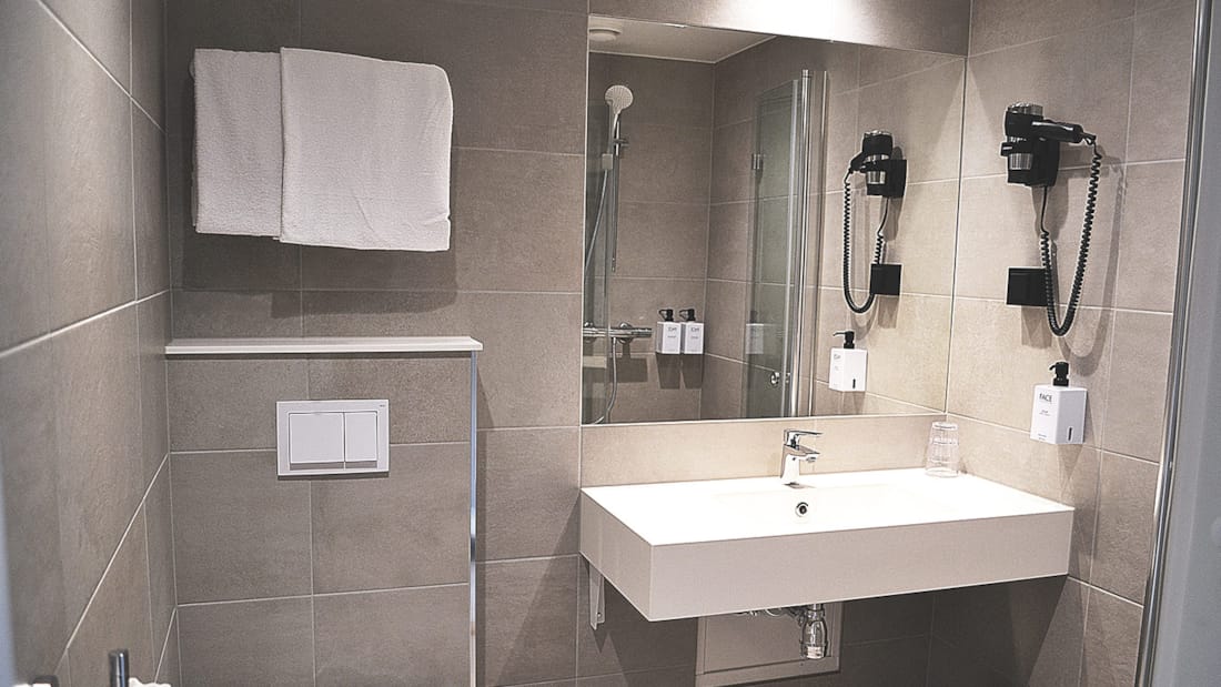 Vask og speil på¨bad på familierom på Hotel Central i ELverum 