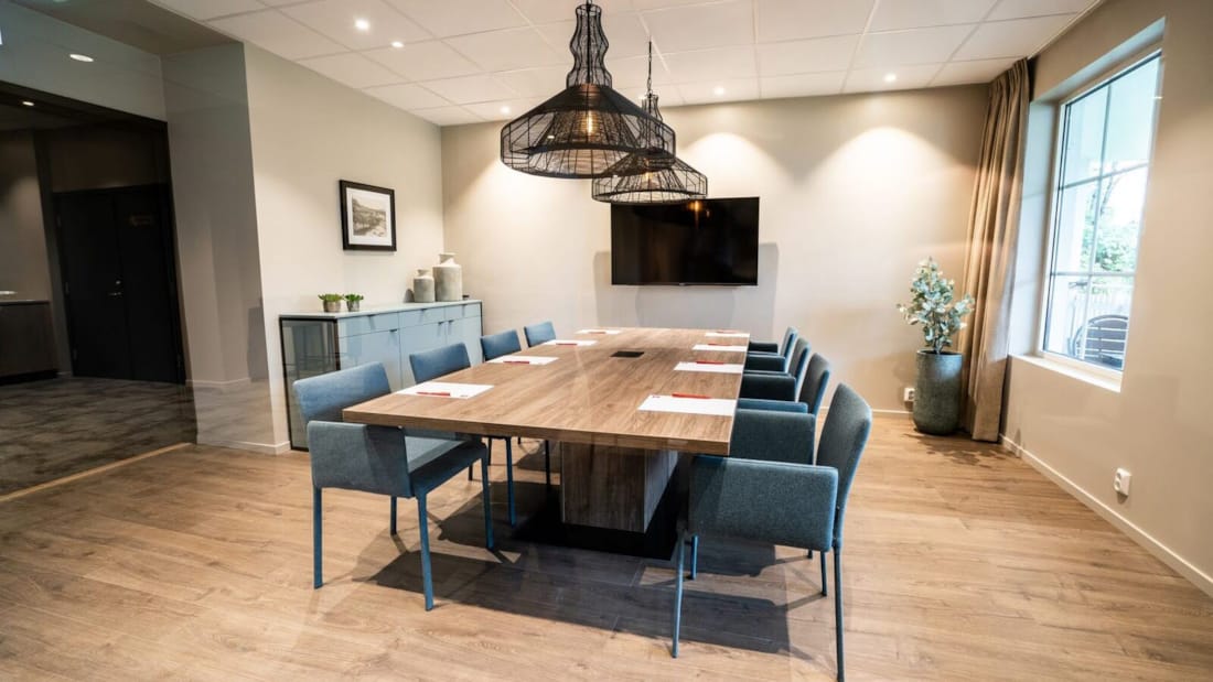Lyst og moderne konferanselokale med styrebord og blå stoler