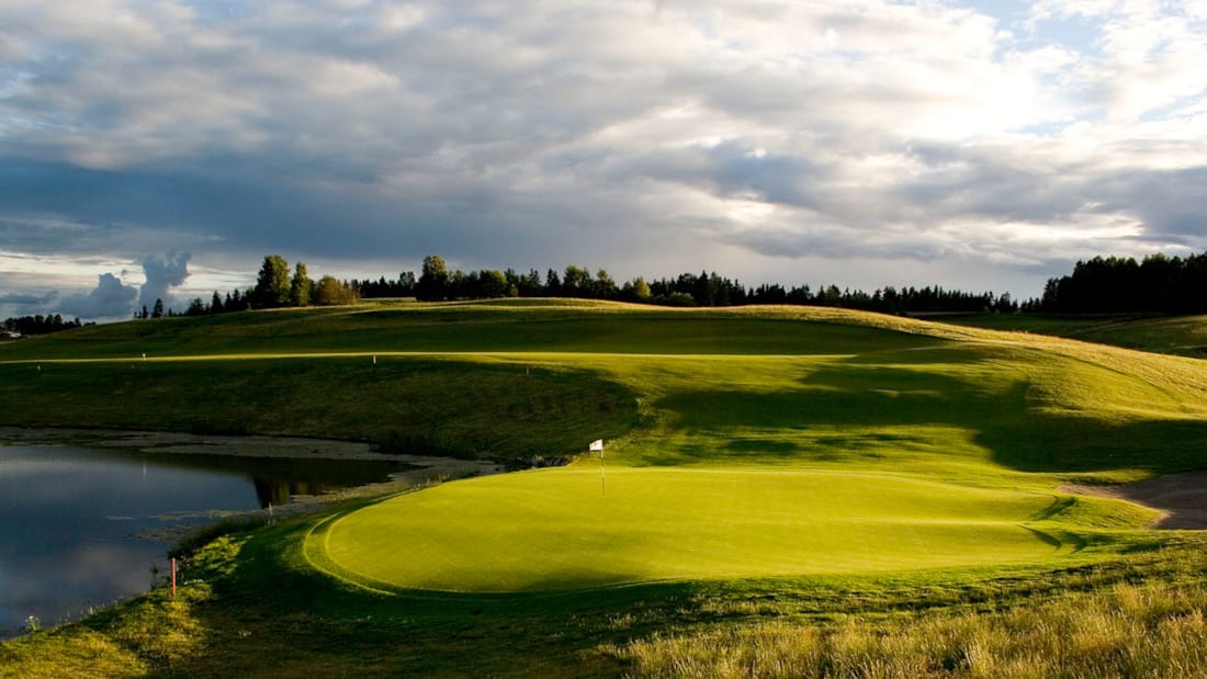En golfbane med en dam og grønt gress.