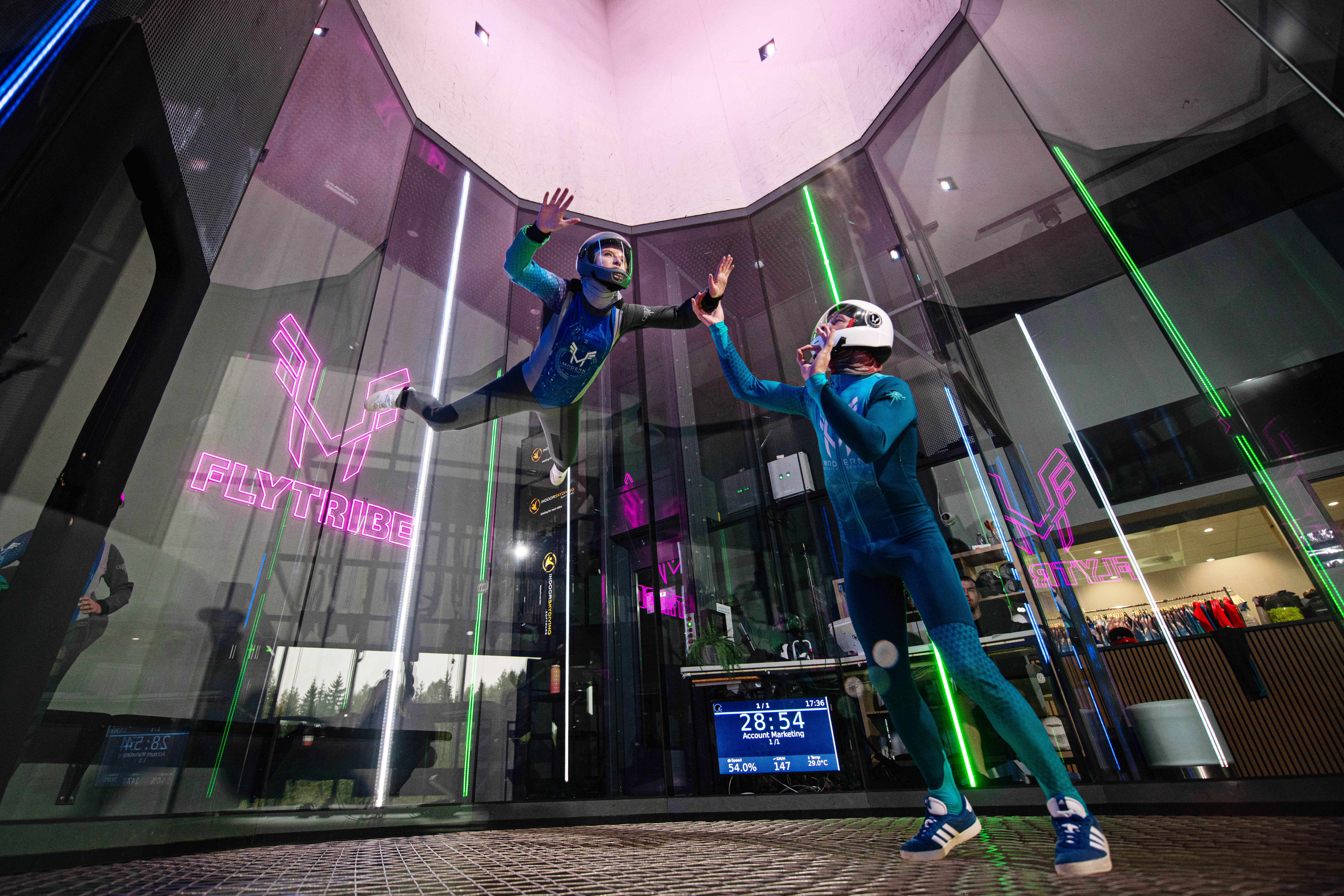 To stykker som svever i en vindtunnel med rosa lys rundt seg.