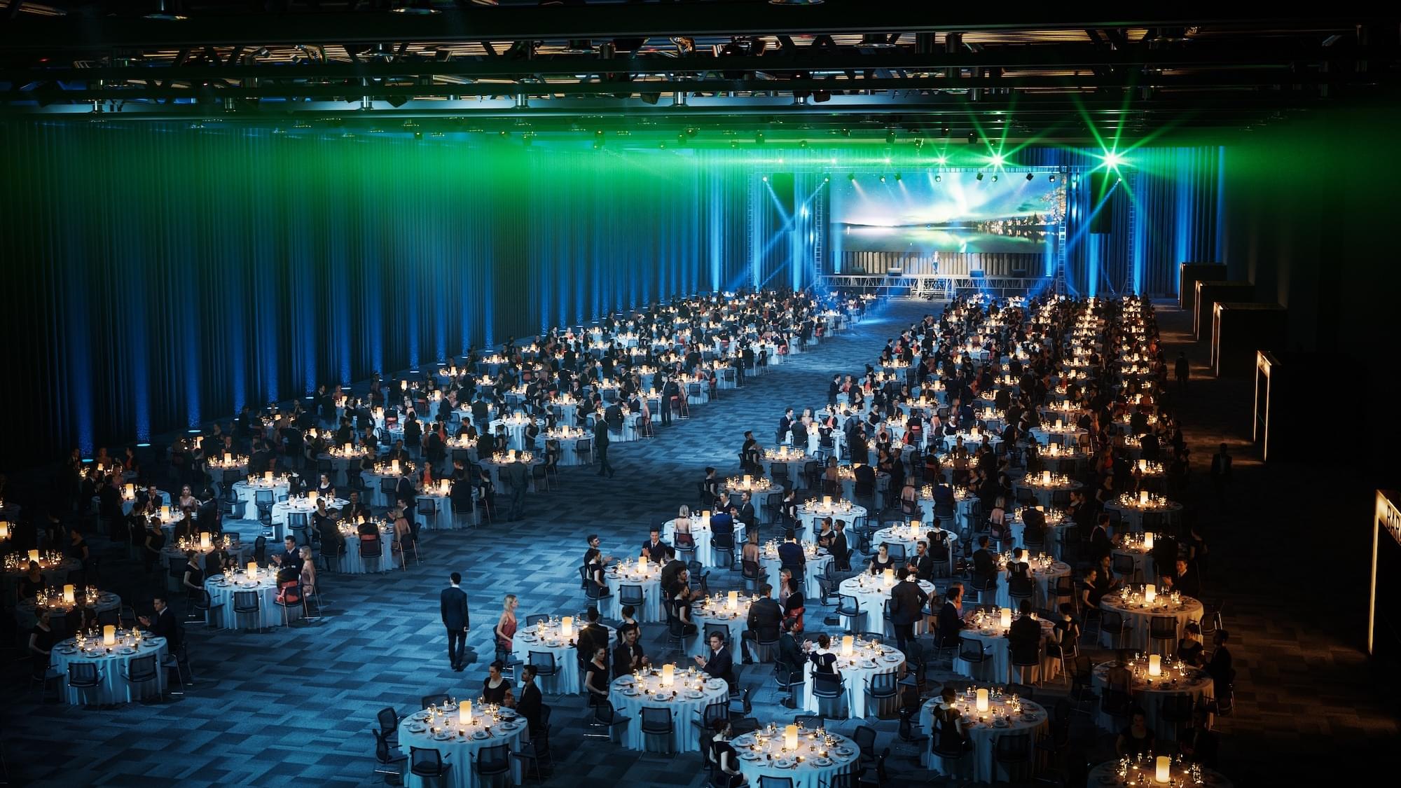 Bankettoppsett for flere tusen mennesker som sitter rundt runde bord i en stor konferansesal.