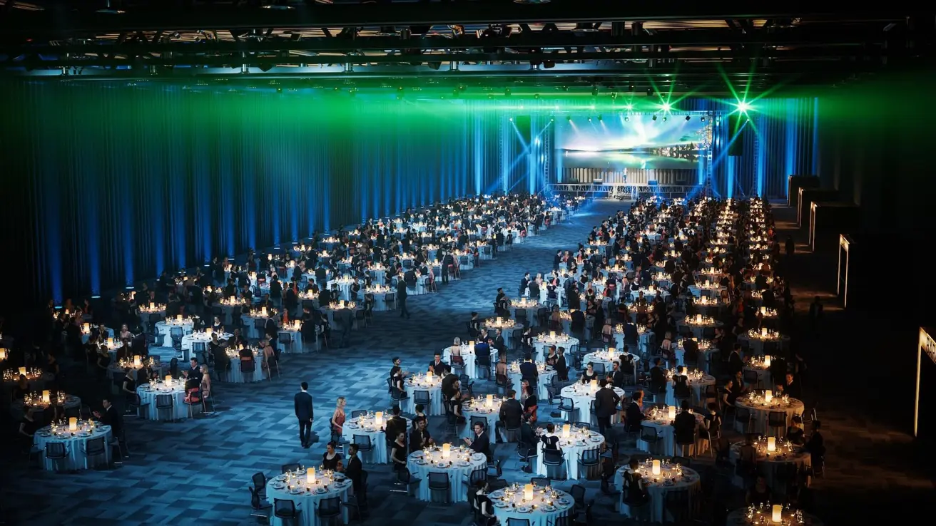 Bankettoppsett for flere tusen mennesker som sitter rundt runde bord i en stor konferansesal.