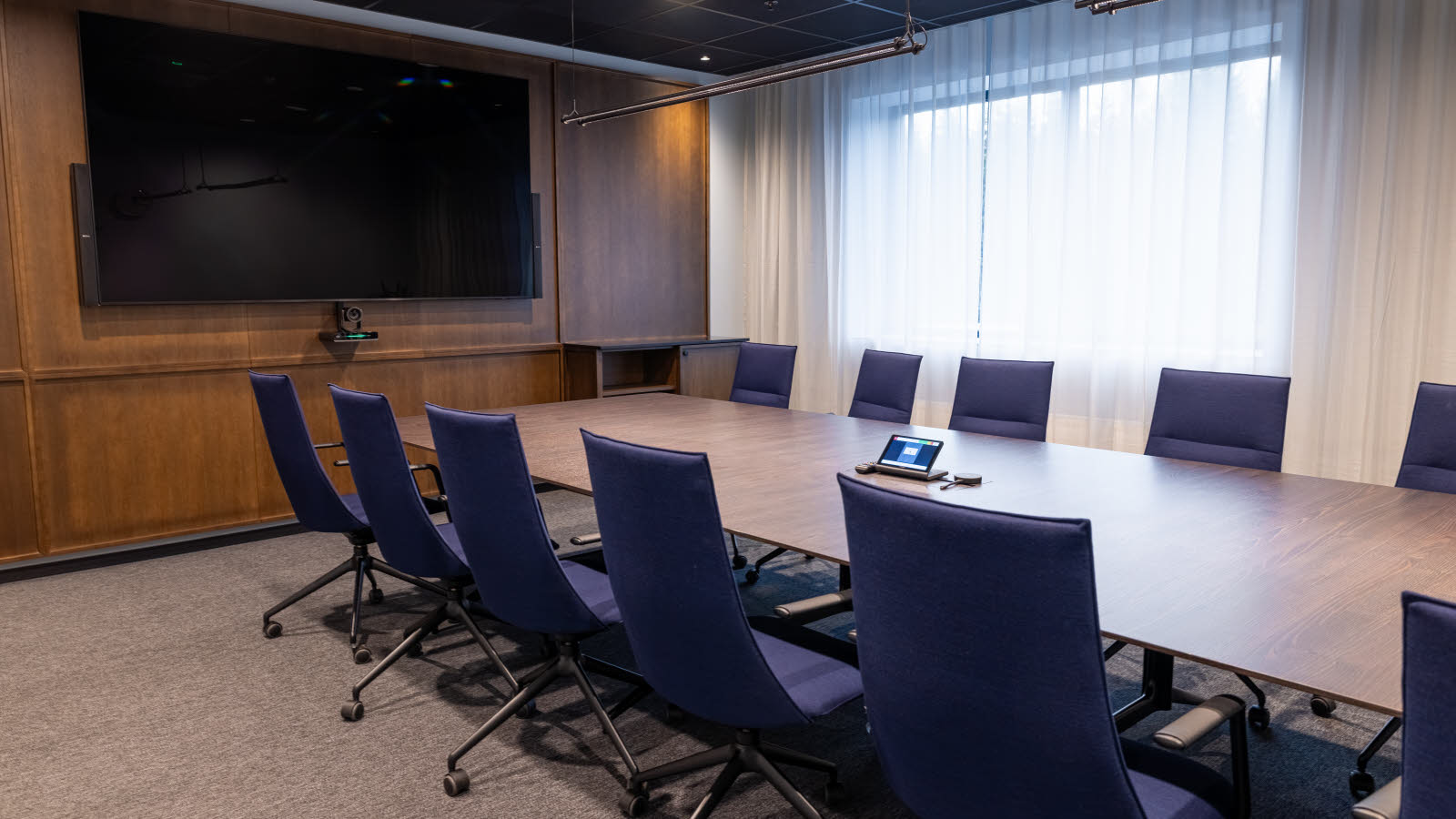 Møterom med tv og stort bord med stoler