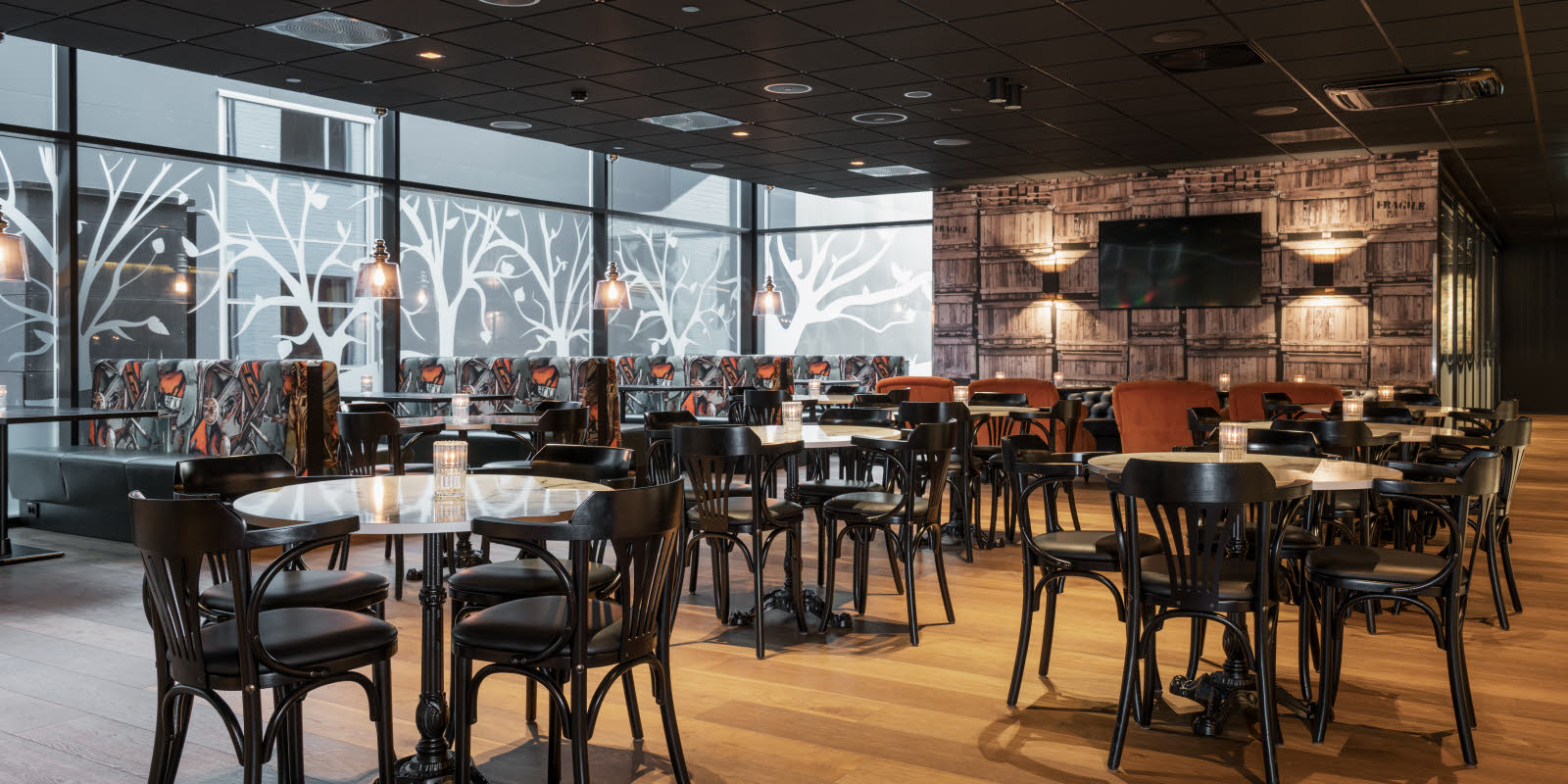 Mørke bord og stoler på restauranten Brasseri Bassit på Thon Hotel Oslo Airport.