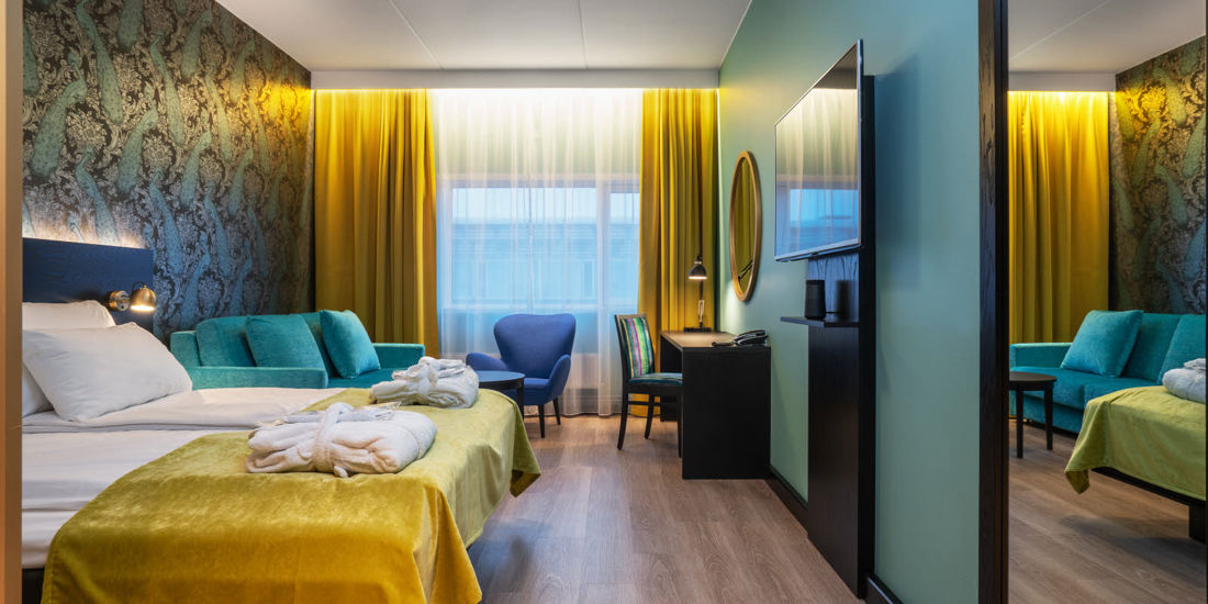 Dobbeltseng med morgenkåper, sofa og sittegruppe på Thon Hotel Oslo Airport