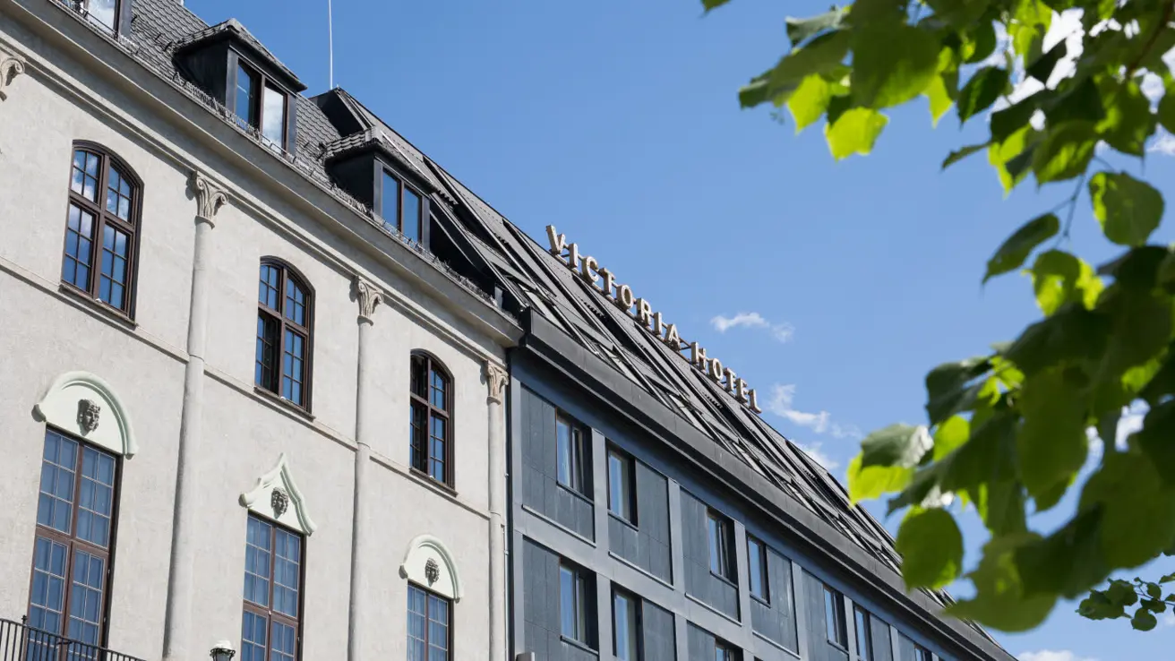 Fasade og frønne trær foran Victoria Hotel Hamar
