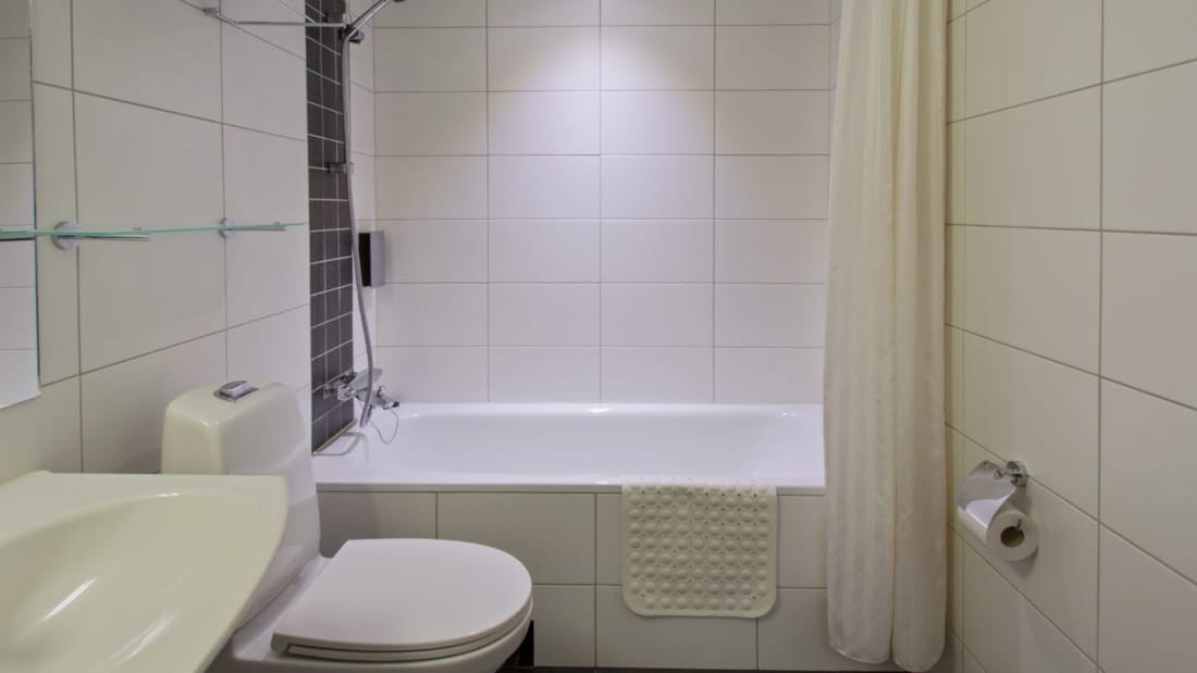 Badekar med dusj, toalett og vask på baderom i Superior room på Hotel Horten