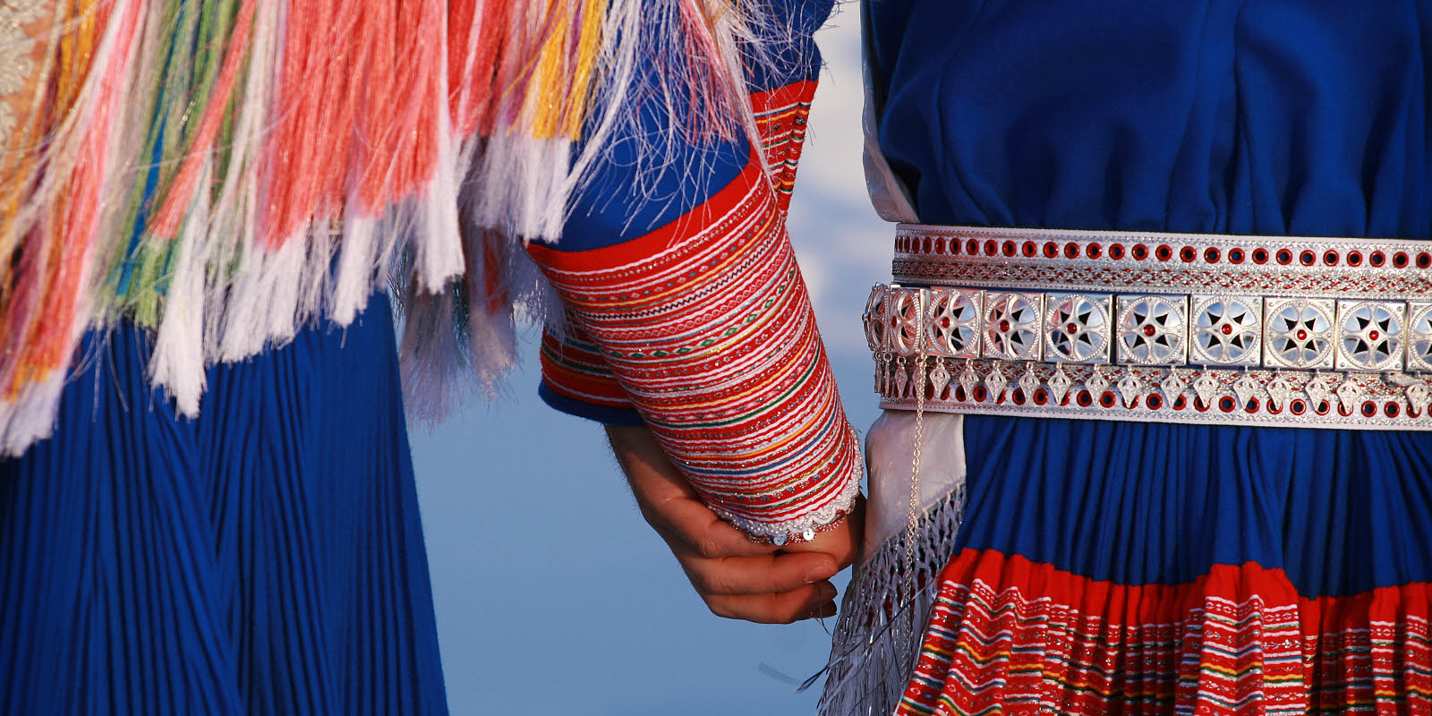 To personer i tradisjonelle klær (kofta er samenes tradisjonelle klesdrakt) holder hender.