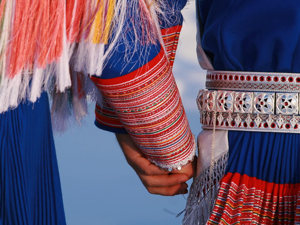 To personer i tradisjonelle klær (kofta er samenes tradisjonelle klesdrakt) holder hender.