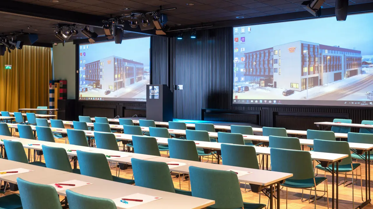 Konferansesal med klasseromsoppsett, to lerret og parkett hos Thon Hotel Kirkenes.