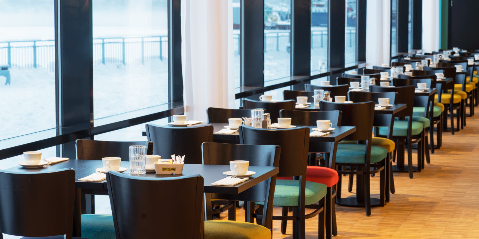 Bord i frokostsal med store vinduer som gir utsikt mot kaia og havet på Thon Hotel Kirkenes ved kaia i Kirkenes sentrum