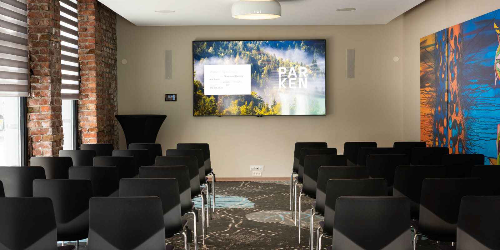 Eik konferanserom i kino-oppsett sett mot skjerm