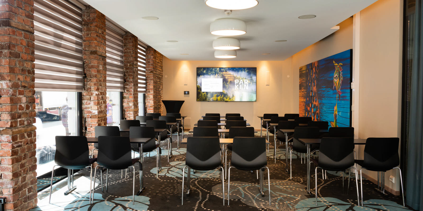 Eik konferanserom med klasserom-oppsett sett mot skjerm