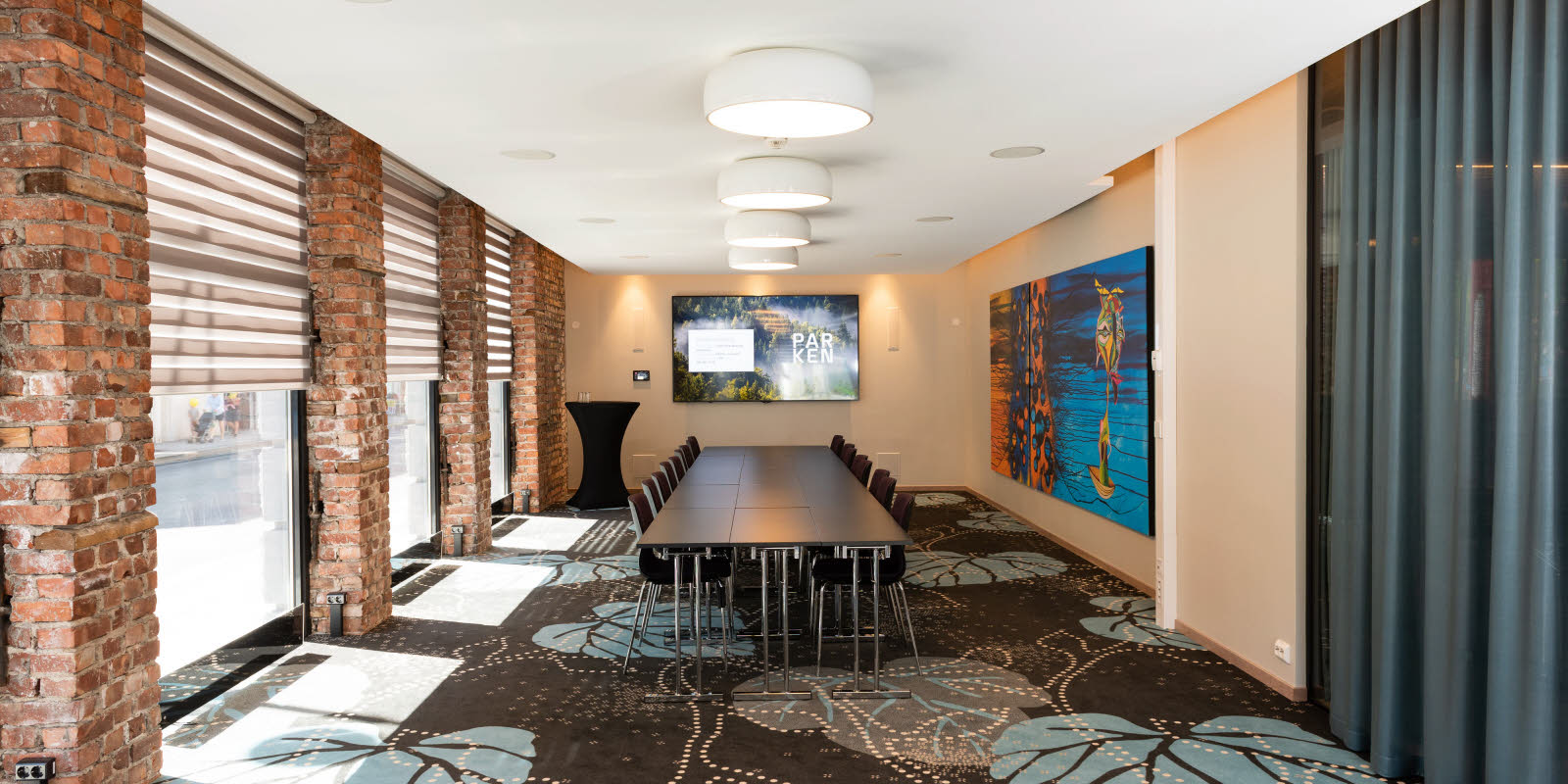 Eik konferanserom med styrebord-oppsett sett mot skjerm