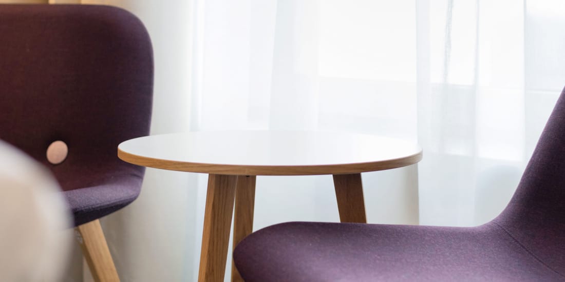 Gjesterom med to lilla stoler og minimalistisk bord på Hotel Parken i Kristiansand sentrum
