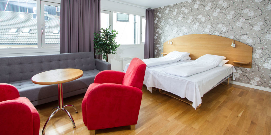 Seng og sofagruppe i familierom på Thon Hotel Storgata.