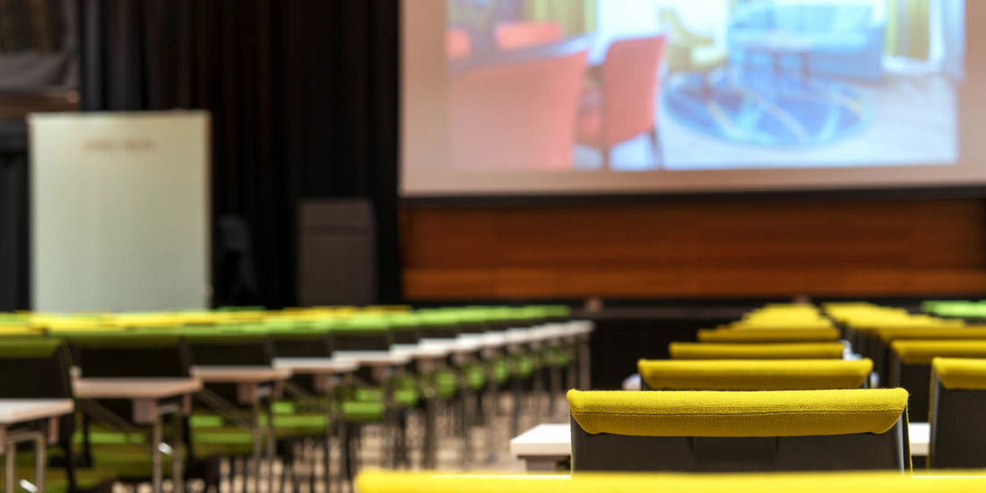 Konferansesal i klasseromoppsett med stort lerret og talerstol