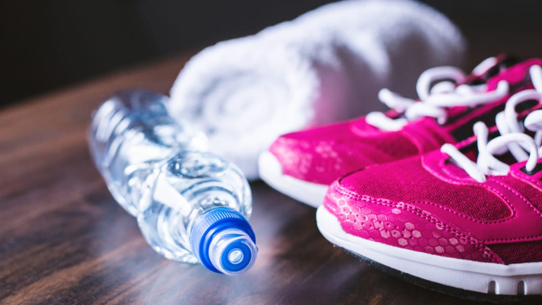 Bilde av vannflaske, sammenrullet håndkle og joggesko.