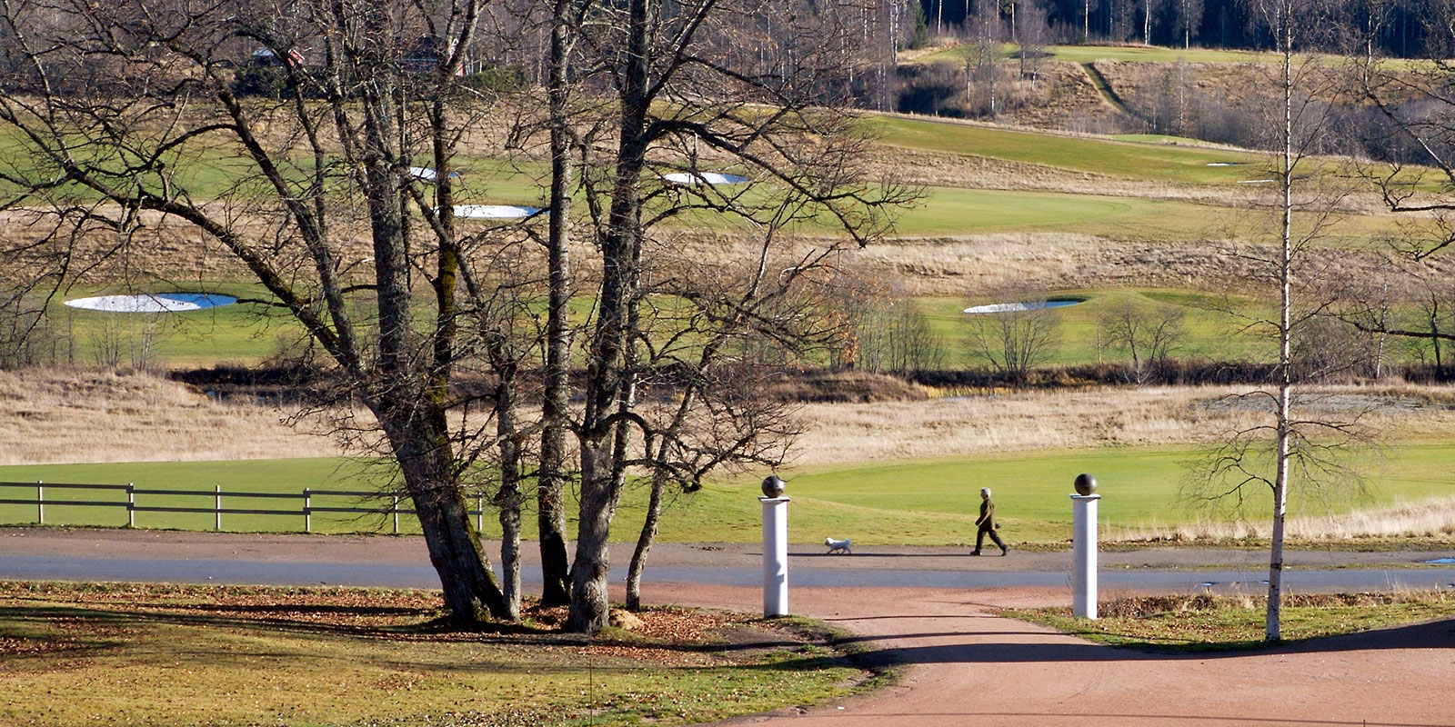 En mann går langs en sti nær en golfbane i skogen.