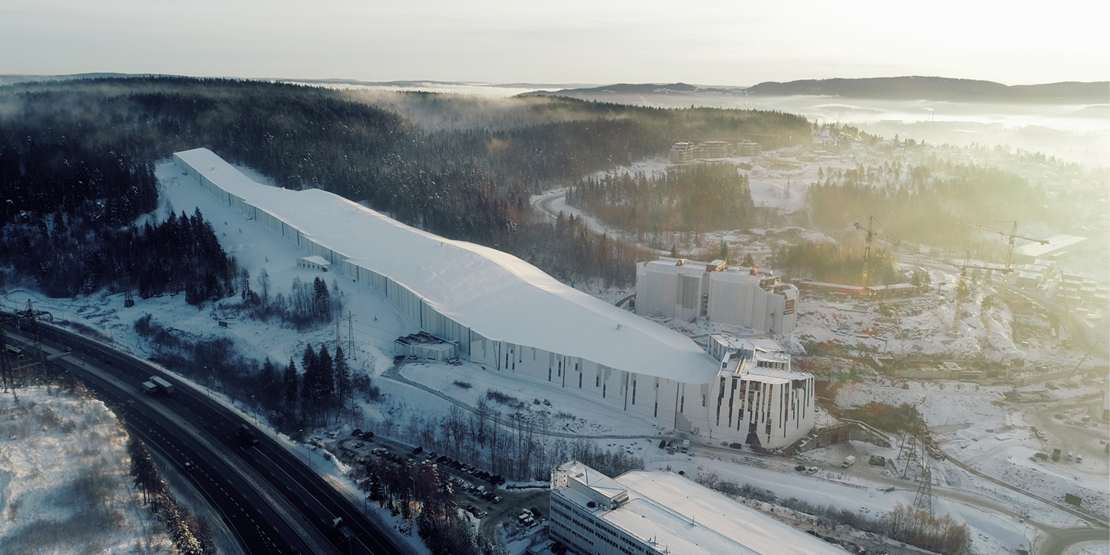 Fasade av Thon Hotel Snø med moderne arkitektur og snødekte fjell i bakgrunnen.