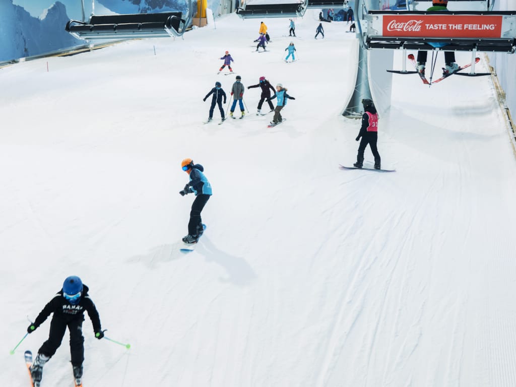 En gruppe mennesker som står på ski og kjører ned en bakke.