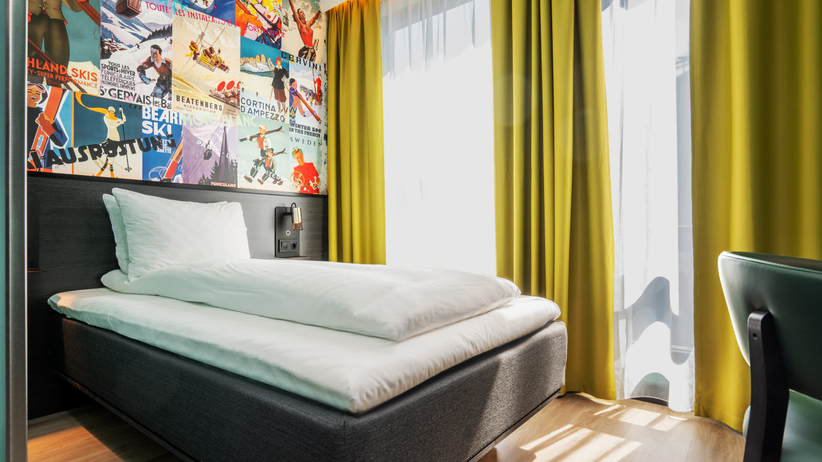 Oppredd dobbeltseng foran to store vinduer med gule gardiner